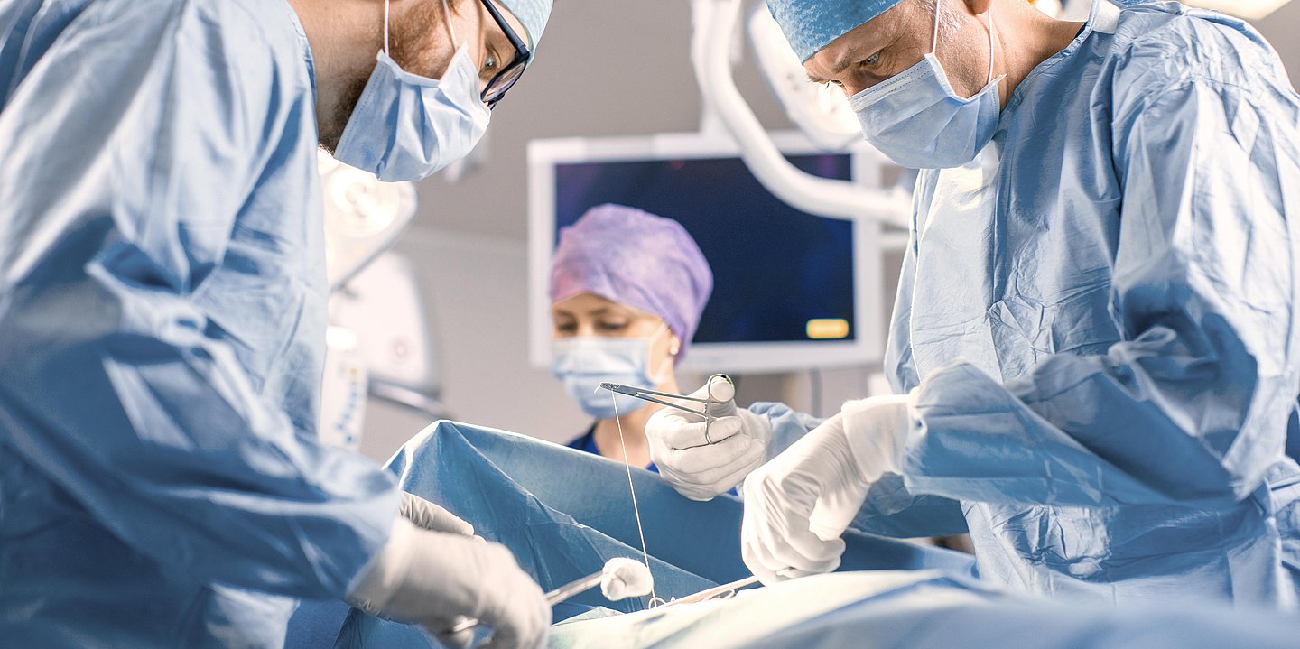 Foto: Klinik-Personal steht in OP-Tracht im Operationssaal.