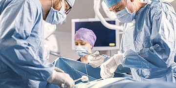 Foto: Klinik-Personal steht in OP-Tracht im Operationssaal.