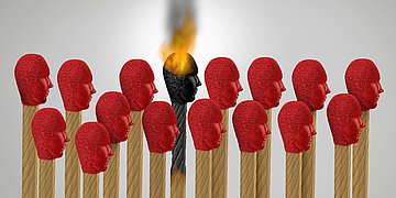 Burn-on Mehrere Streichholzköpfe mit Gesicht stehen nebeneinander, ein Streichholzkopf entzündet sich gerade.
