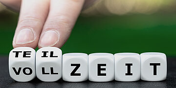 Foto: Sechs wei&szlig;e W&uuml;rfel mit der Aufschrift "Teilzeit/Vollzeit" liegen nebeneinander. Die ersten zwei W&uuml;rfel werden von zwei Fingern angetippt.