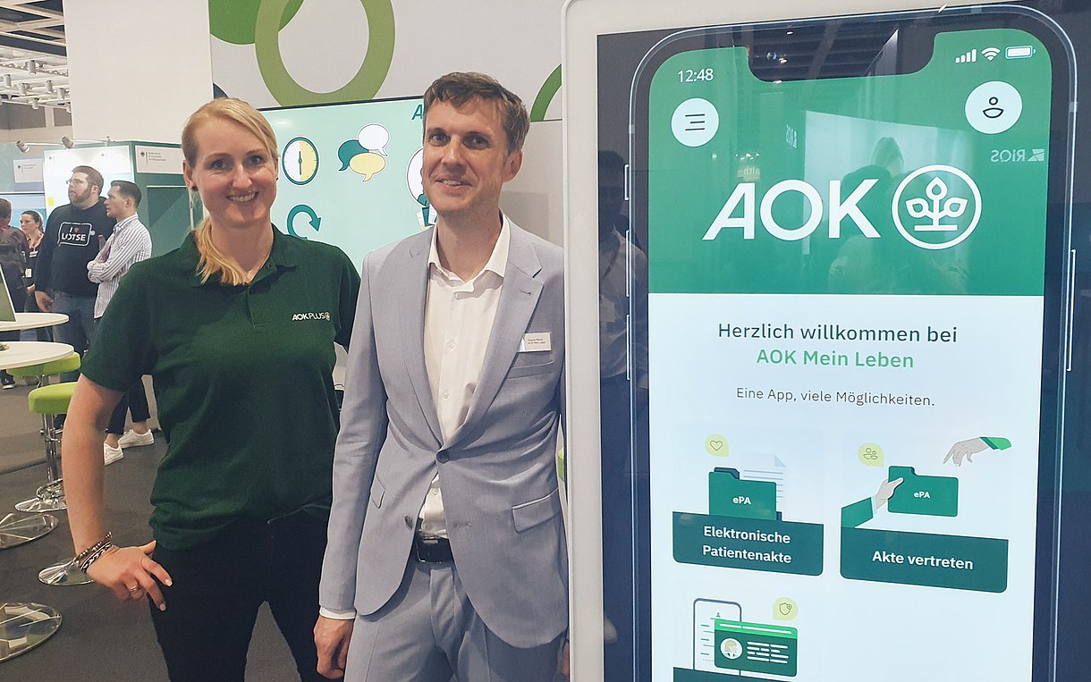 Simone Becherer von der AOK Plus und Pascal Müller von AOK Mein Leben stehen an ihrem Stand auf der DMEA. 