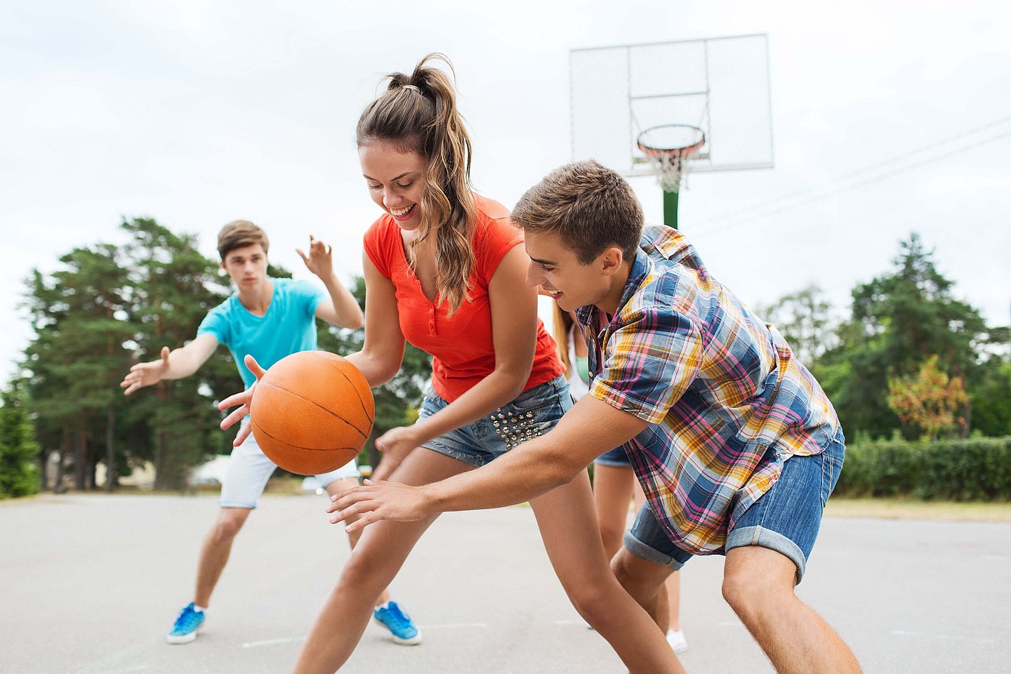 Drei Jugendliche spielen Basketball.