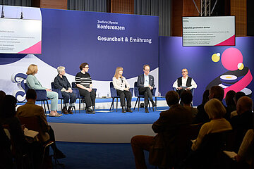 Foto zeigt eine Podiumsrunde aus f&uuml;nf Frauen und einem Mann. Im Vordergrund, etwas im Halbdunkel sieht man Zuschauerinnen und Zuschauer der Veranstaltung &bdquo;Gesundheit und Ern&auml;hrung&ldquo; 