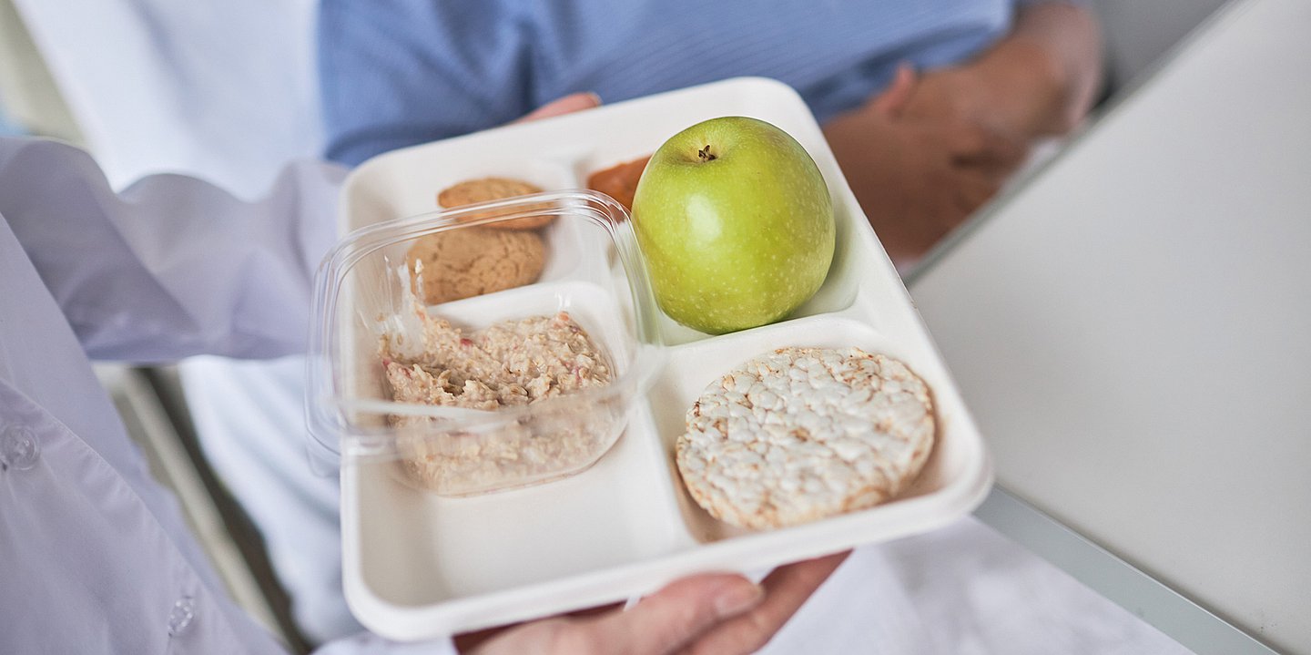 Mangelernährung Foto eines unterteilten Tablets mit gesunden Cerealien, Keksen, einer Reiswaffel und einem Apfel