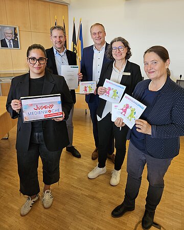 Gruppenfoto mit f&uuml;nf Personen aus verschiedenen &ouml;ffentlichen Einrichtungen der Bodenseeregion, die Marketingprodukte zur Pr&auml;ventionsf&ouml;rderung pr&auml;sentieren.