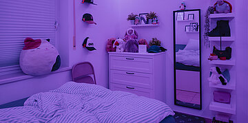 Foto: Blick ins Kinderzimmer der an ME/CFS erkrankten Elli. Das Zimmer ist in abgedunkeltes lilafarbenes Licht getaucht.