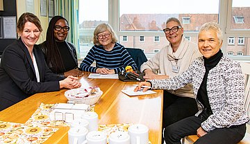 Die Akteurinnen zum Auftakt der landesweiten ‚Woche der pflegenden Angehörigen‘ im Städtischen Krankenhaus in Kiel sitzen im Halbkreis an einem Tisch und sind im Austausch miteinander.