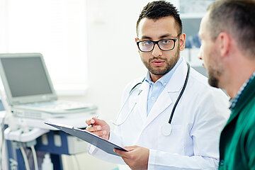 Ein Arzt in Nahaufnahme spricht in einem Behandlungsraum mit einem Patienten.
