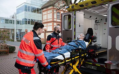zwei Notfallsanit&auml;ter schieben eine Pritsche mit einem Patienten aus einem Rettungswagen.