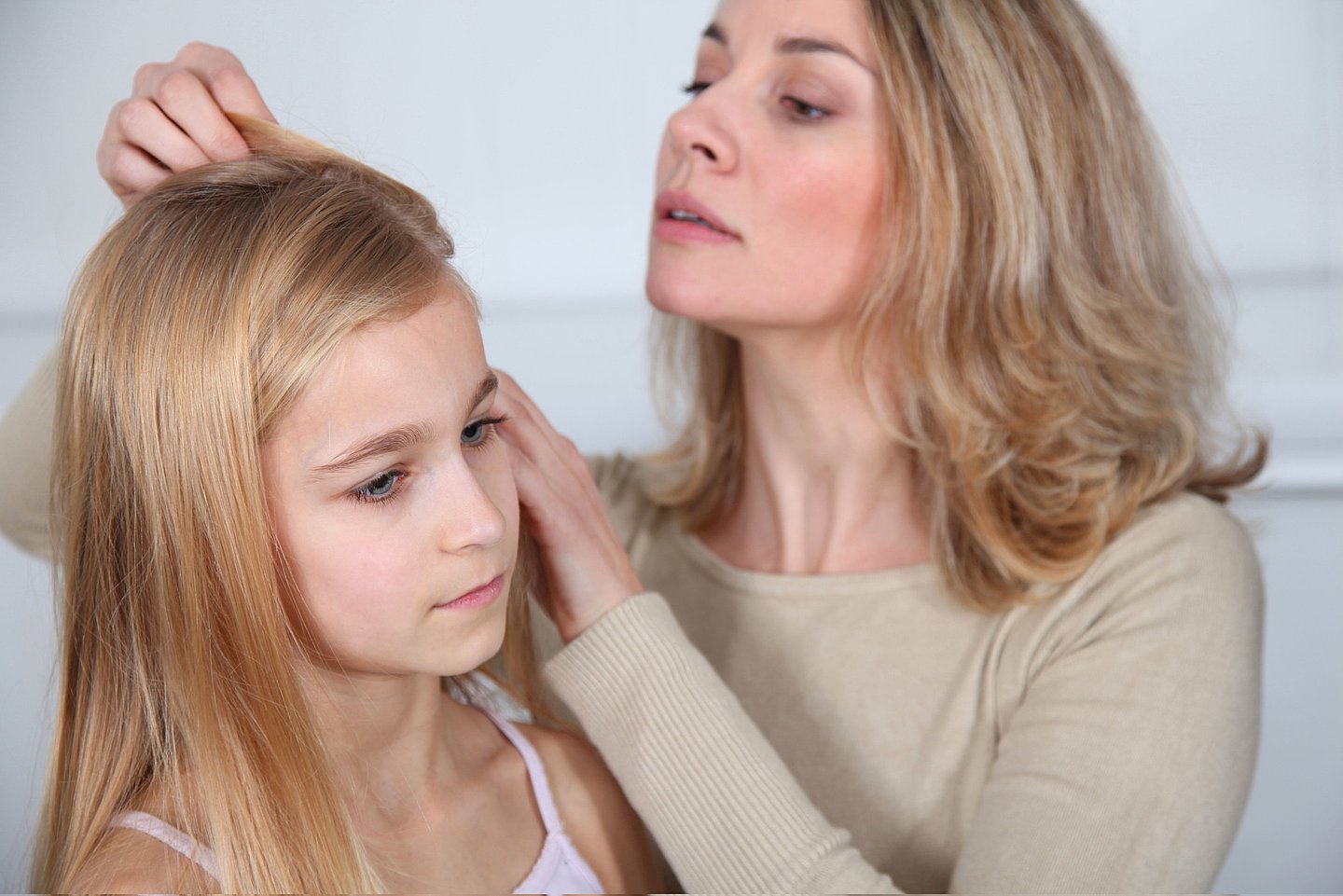 Das Foto zeigt eine Mutter, die bei ihrer Tochter mit einem Nissenkamm die Haare nach Läusen absucht.