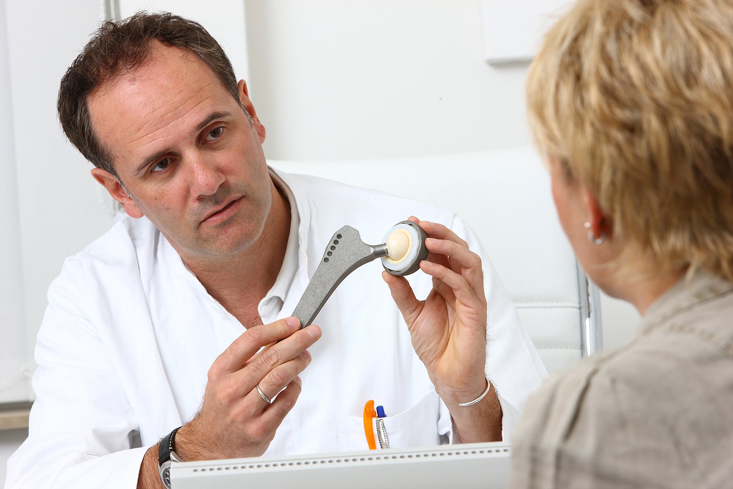 Ein Arzt erklärt einer Patientin die Funktion eines künstlichen Hüftgelenks (TEP).