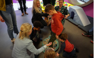 Kind auf Spielger&auml;t mit helfenden Erwachsenen