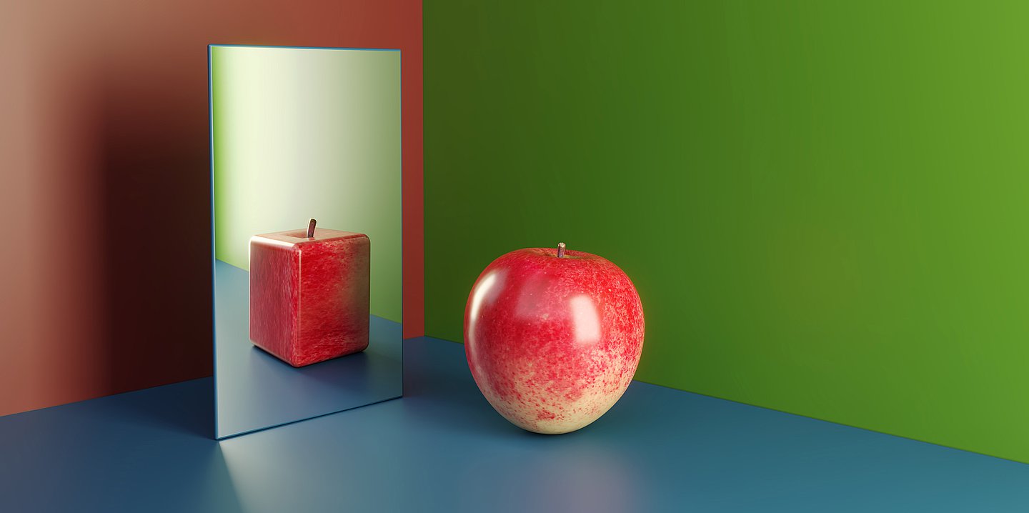 Foto: Ein runder Apfel spiegelt sich in einem Spiegel als eckiger Apfel.