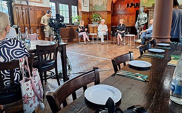 Momentaufnahme der Podiumsdiskussion zum Thema Gender-Meizin: Vier Personen sitzen nebeneinander. Im Vordergrund stehen Tische f&uuml;r das Publikum.