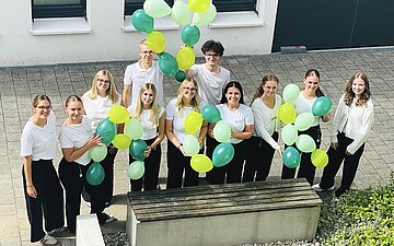 Gruppenfoto der 11 neuen Azubis der AOK Bodensee-Oberschwagen. Sie halten Luftballons in ihren H&auml;nden.