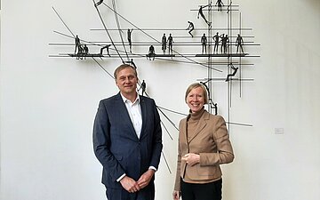 AOK-Gesch&auml;ftsf&uuml;hrer Markus Packmohr und Landr&auml;tin Stefanie B&uuml;rkle stehen vor einem an einer Wand montierten Kunstobjekt.