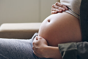 Eine schwangere Frau streichelt ihren Babybauch.