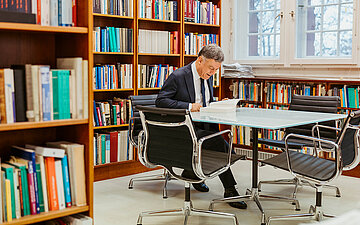 Giovanni Maio sitzt an einem Tisch und liest in einem Buch.