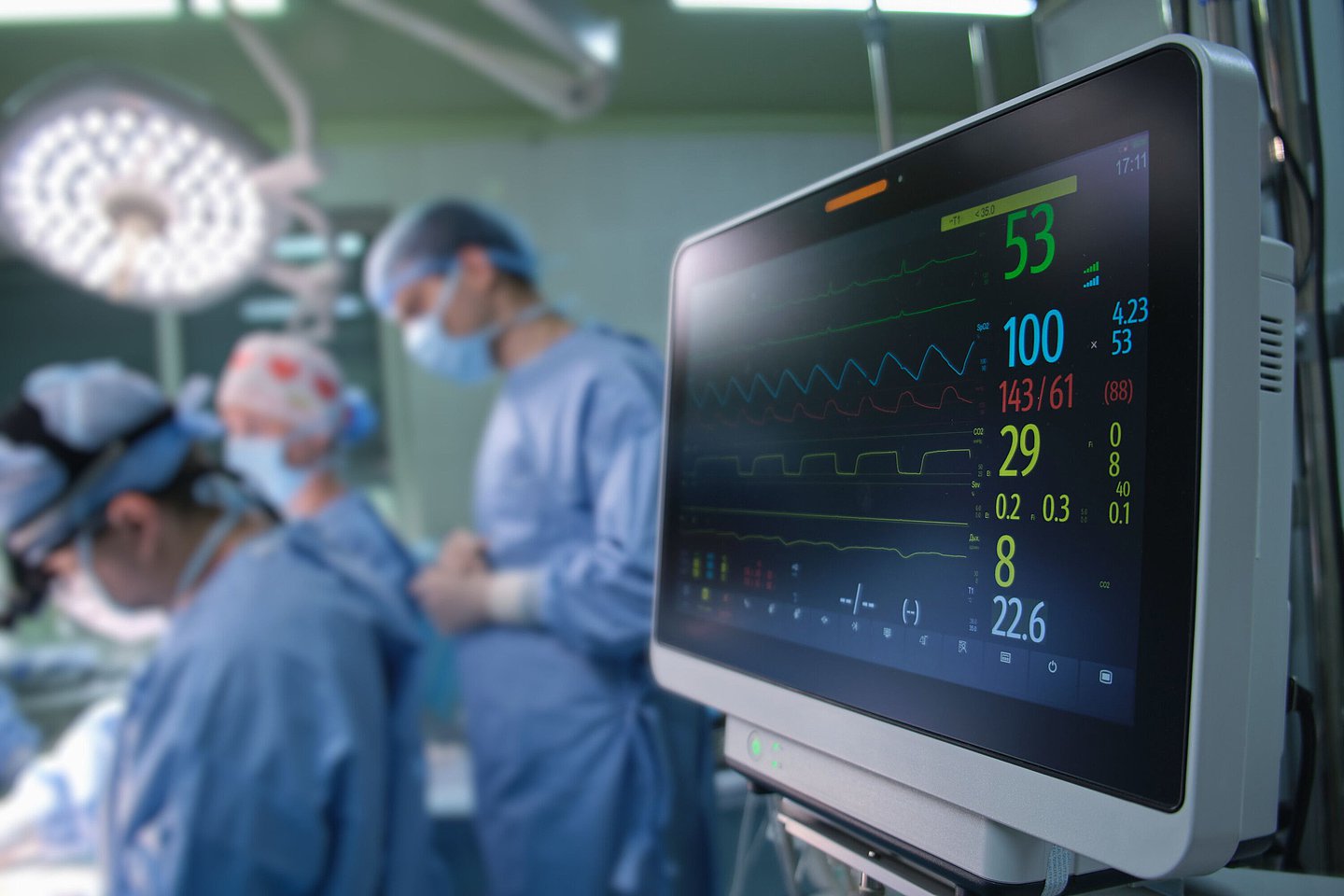 Auf dem Foto ist ein OP-Saal mit einem Ärzteteam zu sehen, im Vordergrund zeigt ein Monitor die Vitalwerte an.