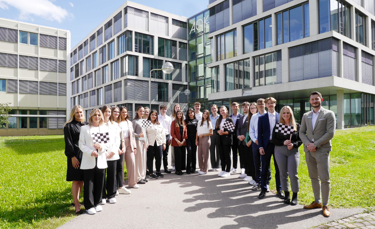 Eine große Gruppe von Auszubildenden der AOK Baden-Württemberg steht vor dem Gebäude der AOK-Hauptverwaltung in Stuttgart.