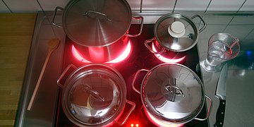 Auf den heißen Platten eines Elektroherdes stehen Töpfe.