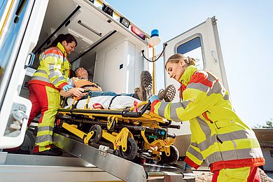 Zwei Sanitäterinnen transportieren einen Verletzten in den Rettungswagen.