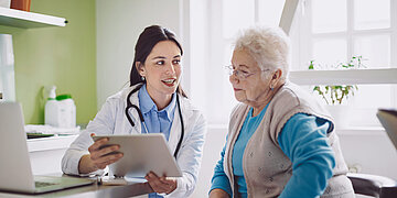 Eine Haus&auml;rztin ber&auml;t eine &auml;ltere Patientin im Gespr&auml;ch. 