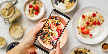 Foto: Eine Person macht Fotos von einem gesunden Fr&uuml;hst&uuml;ck, das extra sch&ouml;n angerichtet ist