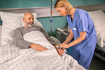 Entfernung der Prostata Pflegerin versorgt peripheren Venenkatheter bei einem Patienten im Krankenhaus