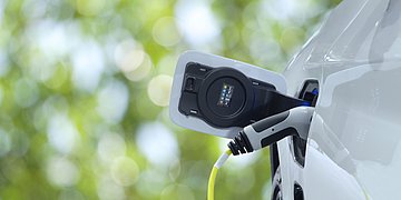 Foto: Ein weißes E-Auto lädt an einer Ladestation.