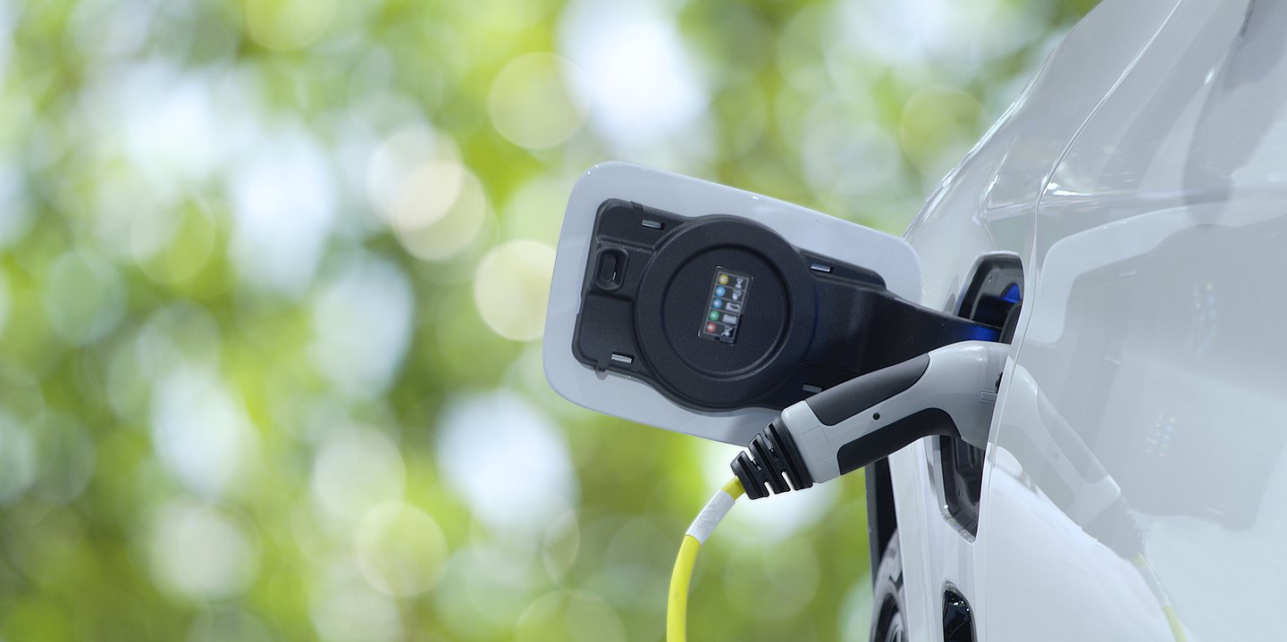 Foto: Ein weißes E-Auto lädt an einer Ladestation.
