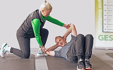 Ein Mann liegt auf dem Boden, Frau beugt sich über ihn