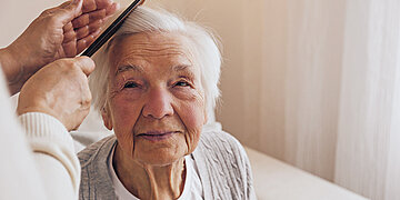Foto einer alten Damen, der die Haare geb&uuml;rstet werden