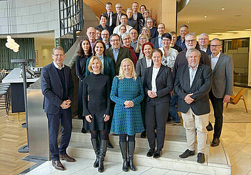 Das Gruppenfoto zeigt alle Beteiligten des Paktes f&uuml;r Gesundheit in Hessen auf einer Treppe in der Eingangashalle eines B&uuml;rogeb&auml;udes