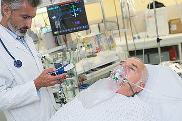 Mit COPD im Krankenhaus Ein Arzt versorgt einen COPD-Patienten im Krankenhaus mit Sauerstoff.