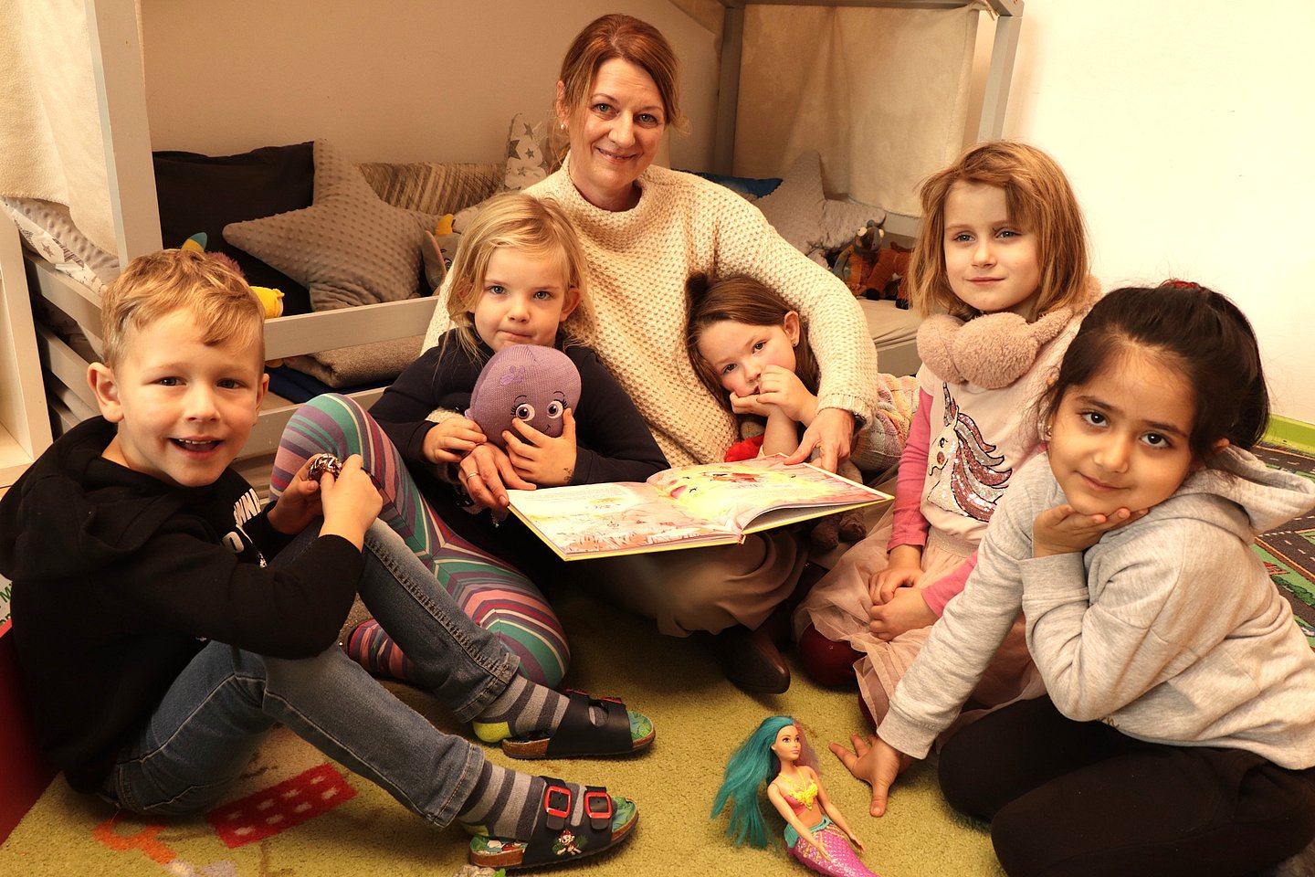 Das Foto zeigt die AOK-Landesdirektorin Iris Kröner beim Vorlesen umringt von Kindergartenkinder. 