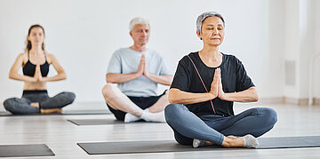 Das Foto zeigt M&auml;nner und Frauen beim Yoga.