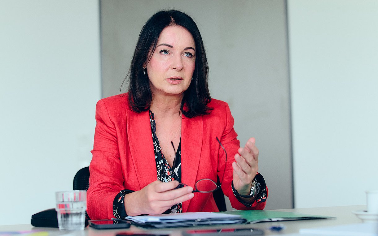 Foto: Britta Müller, Ministerin für Gesundheit und Soziales des Landes Brandenburg, am Tisch, sie erklärt etwas.