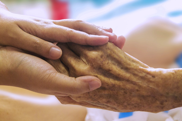 Ambulante Hospizdienste Zwei Junge Hände halten zärtlich eine sehr alte Hand.