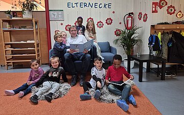 AOK-KundenCenter-Leiter Bernd Hierlemann liest einer Gruppe von Kindern aus einem Buch vor.