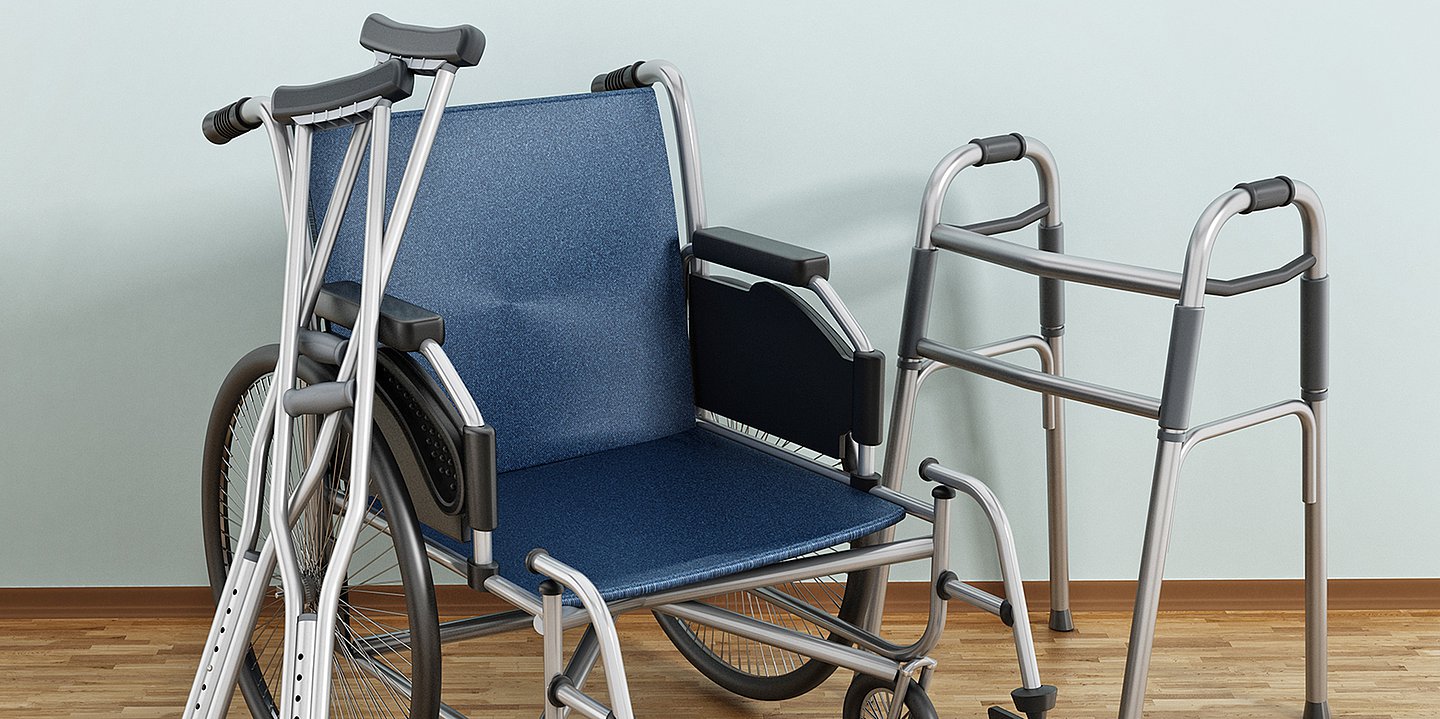 Foto: Krücken, Rollstuhl und Laufhilfe stehen nebeneinander.