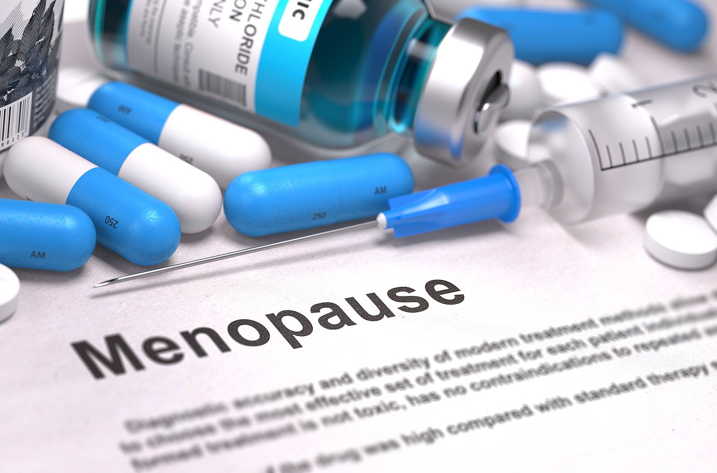 Foto  zeigt Kapseln und Tabletten auf einer Unterlage, dazwischen ein Zettel mit der Aufschrift 'Menopause'.