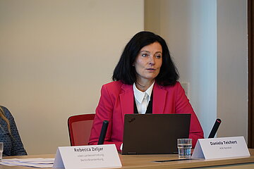 Daniela Teichert, Vorstandsvorsitzende der AOK Nordost, sitzt w&auml;hrend einer Pressekonferenz an einem Tisch, vor ihr ist ein Laptop aufgeklappt. Sie spricht mit Medienvertretenden, die im Bild nicht zu sehen sind.