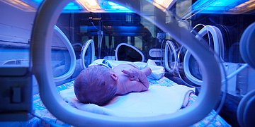 Foto: Ein frühgeborenes Baby liegt in einem Brutkasten.