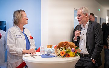 Eröffnungsfeier in einem Krankenhaus. Eine Ärztin und ein Mann im Gespräch.
