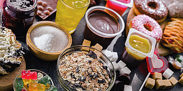 Foto: Auf einem Foto sind viele S&uuml;&szlig;igkeiten zu sehen, darunter Pudding, Donuts, Gummib&auml;ren und Limonade.