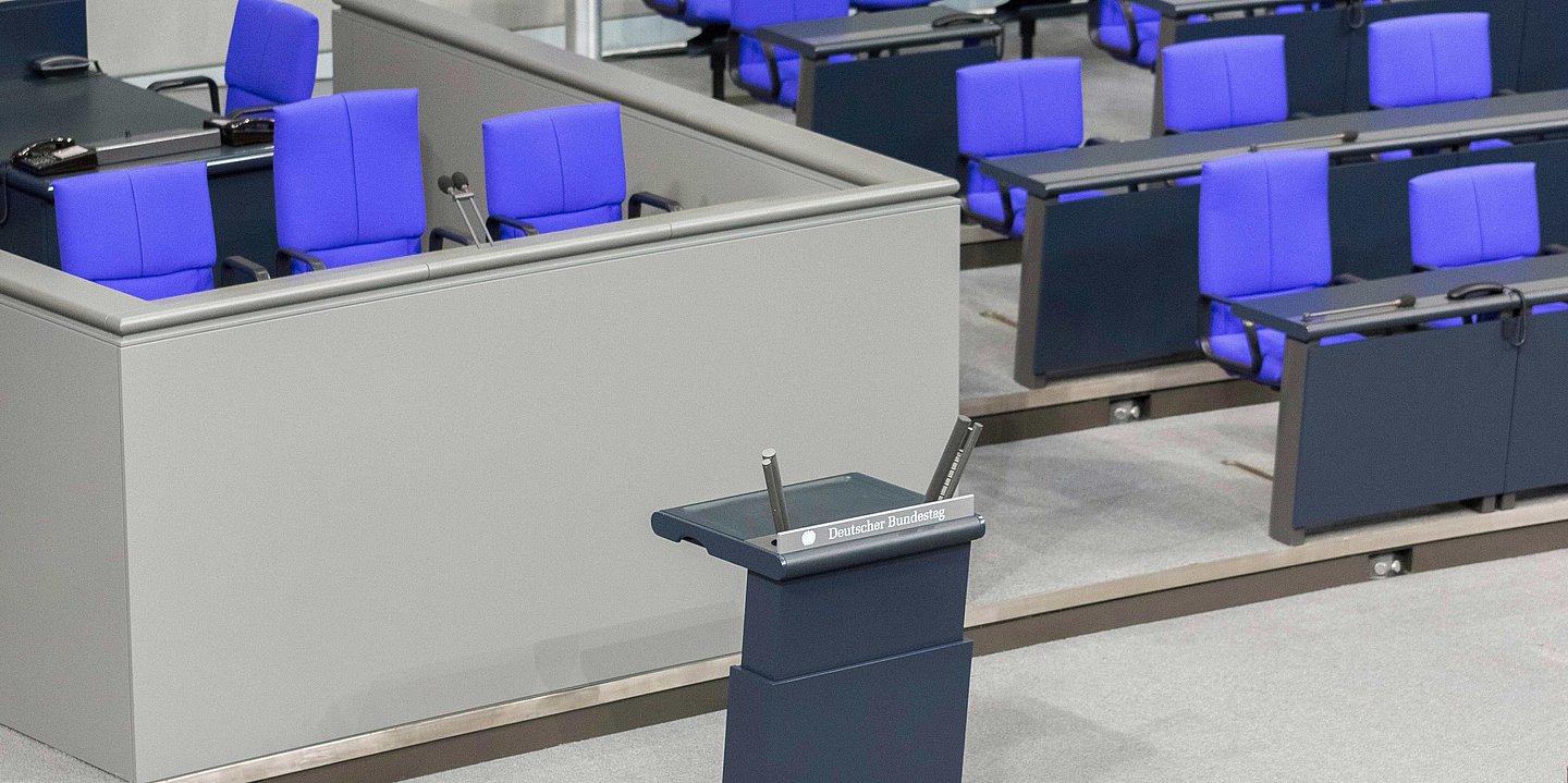 Innenansicht vom Bundestags ohne Menschen. Das Sprecherpult ist in der Mitte des Bildes.