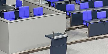 Innenansicht vom Bundestags ohne Menschen. Das Sprecherpult ist in der Mitte des Bildes.