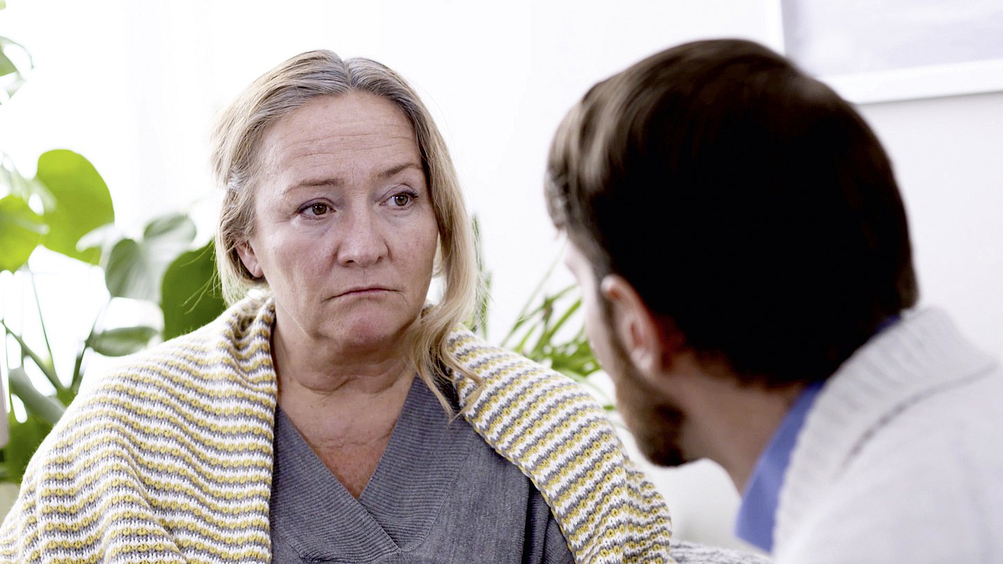 Ein Mann und eine ältere Frau im Gespräch. Die ältere Frau guckt traurig.