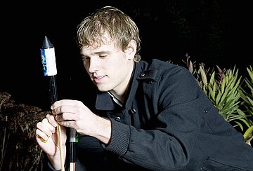 Jungendlicher z&uuml;ndet eine Feuerwerksrakete